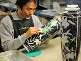An artisan at Noritake paints ceramic.